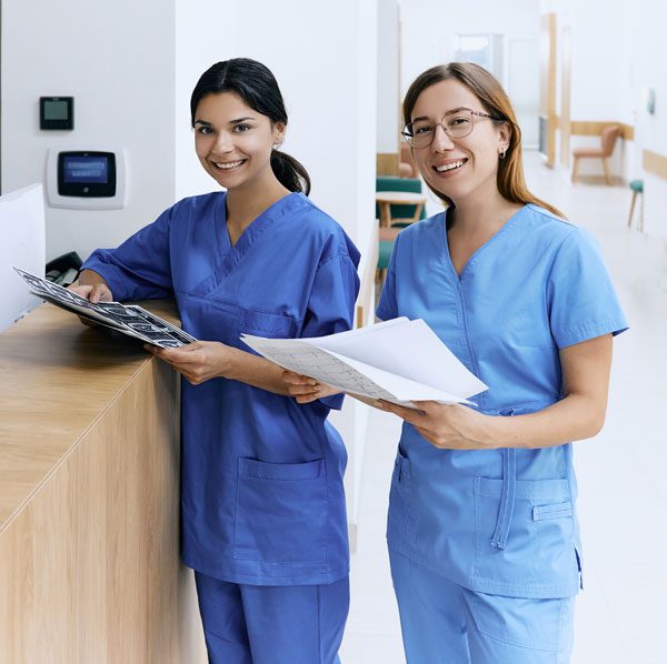 2 medical workers smiling and holding papers