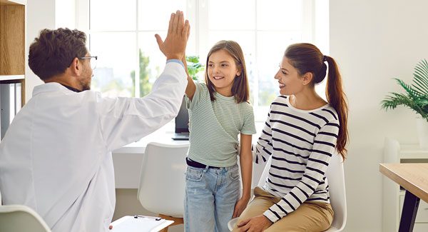 Physician giving a high five to a young patient.
